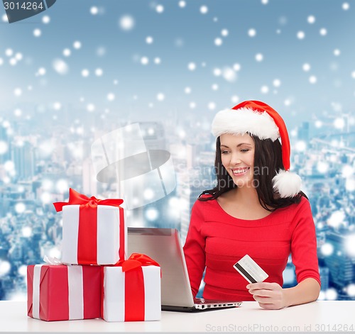 Image of smiling woman with gifts, laptop and credit card