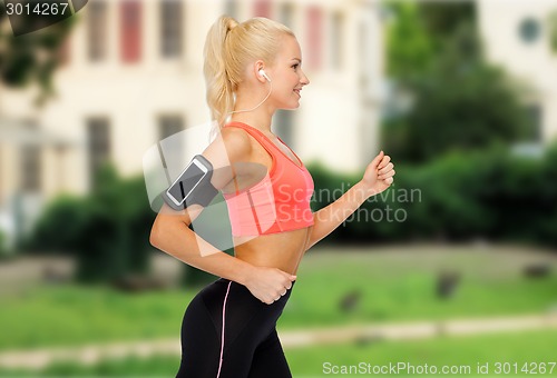 Image of sporty woman running with smartphone and earphones