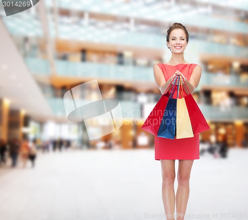 Image of smiling elegant woman in dress with shopping bags