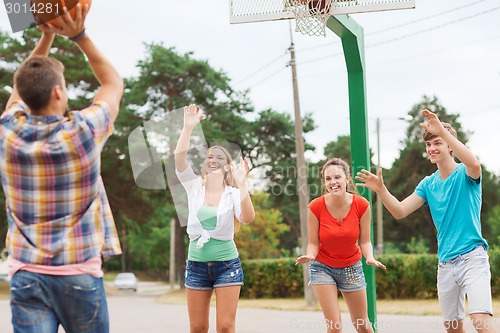 Image of group of smiling teenagers playing basketball