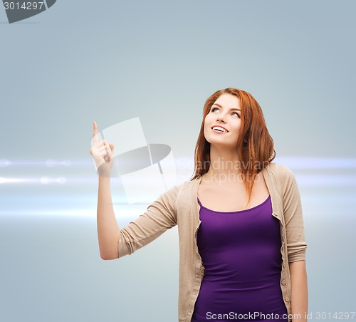 Image of smiling teenage girl pointing finger up