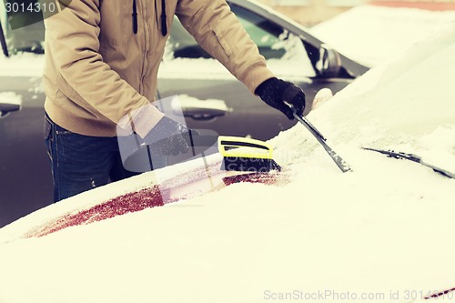 Image of closeup of man cleaning snow from car