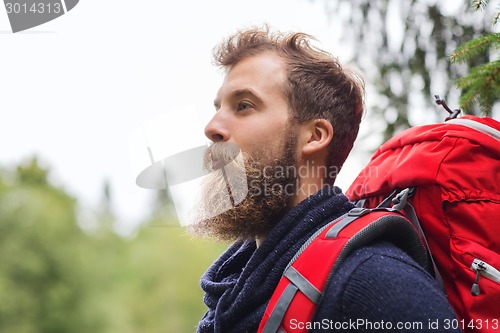 Image of smiling man with beard and backpack hiking