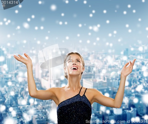 Image of smiling woman raising hands and looking up