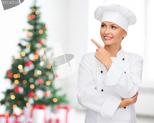 Image of smiling female chef dreaming  pointing finger up