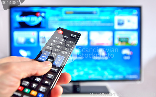 Image of Smart tv and hand pressing remote control