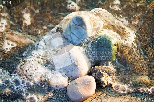Image of Small sea stones on the seashore, covered with a sea wave.