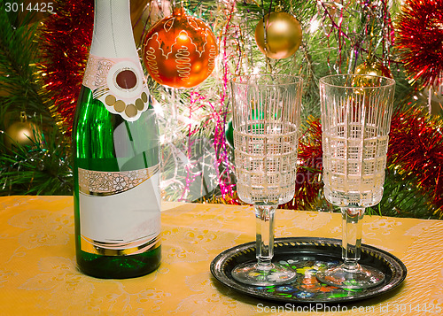 Image of Christmas holiday, wine and glasses near a Christmas fir-tree.