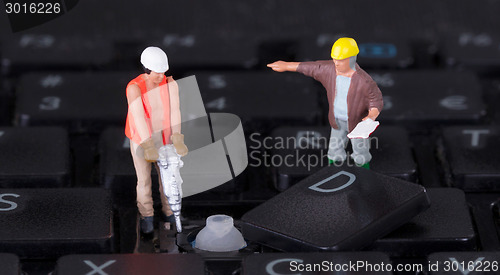 Image of Miniature workers with drill working on keyboard