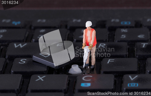 Image of Miniature worker with drill working on keyboard