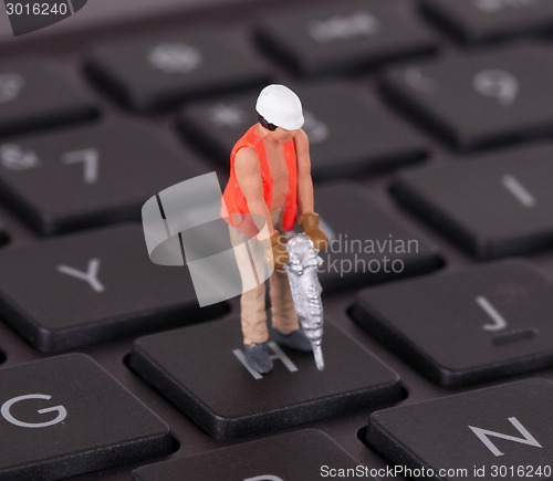 Image of Miniature worker with drill working on keyboard