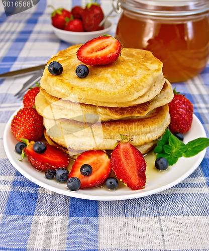 Image of Flapjacks with strawberries and blueberries on blue tablecloth