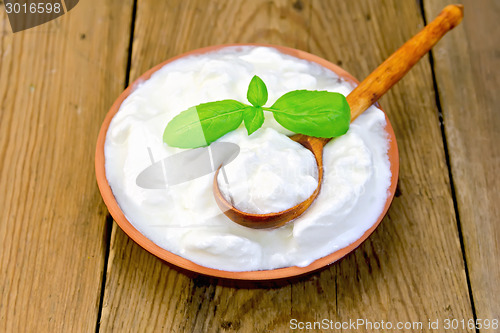 Image of Yogurt in clay bowl with spoon on board