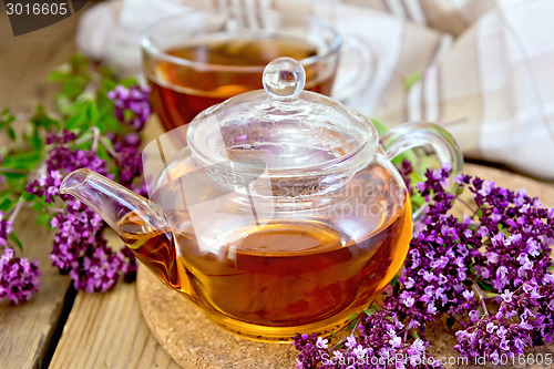 Image of Tea of oregano in glass teapot on board with cup