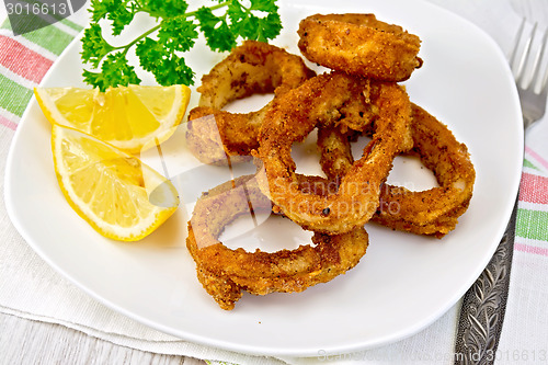 Image of Calamari fried with lemon and fork on plate