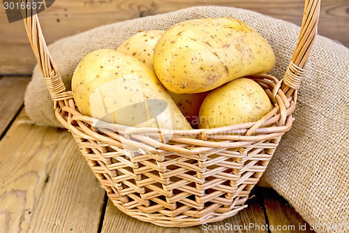 Image of Potatoes yellow in basket with burlap on board