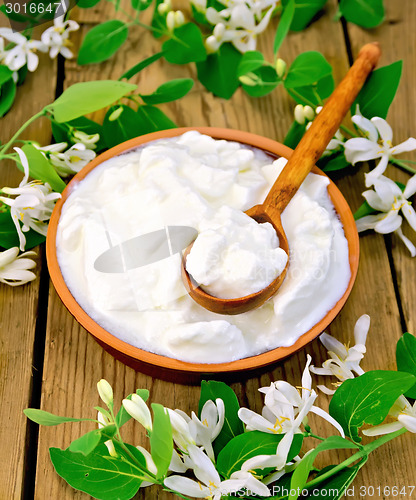 Image of Yogurt in clay bowl with spoon and flowers of honeysuckle