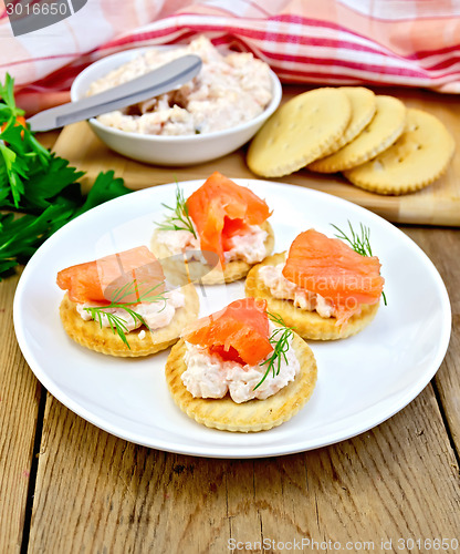 Image of Crackers with cream and salmon in plate on board