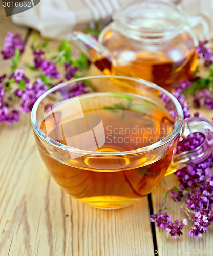 Image of Tea of oregano in glass cup on board with teapot