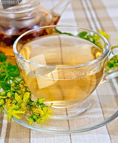 Image of Tea from tutsan in glass cup and teapot on tablecloth