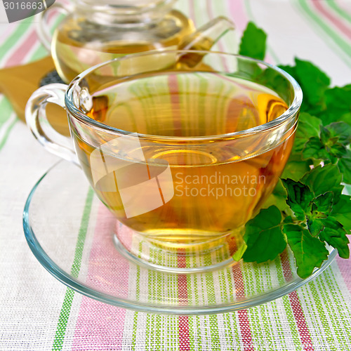 Image of Tea with mint in cup and teapot on tablecloth