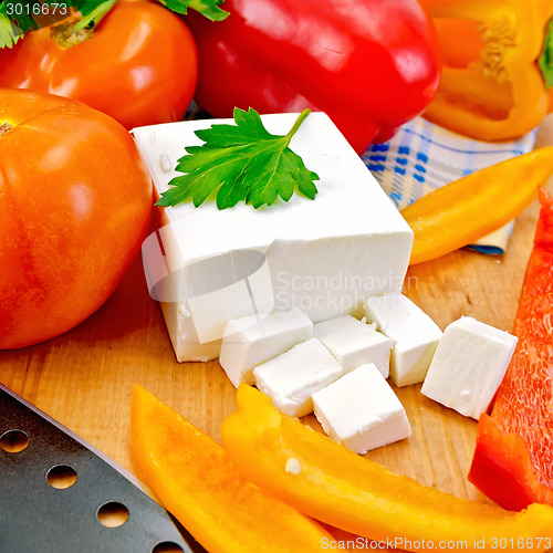 Image of Feta with vegetables and herbs on wooden board