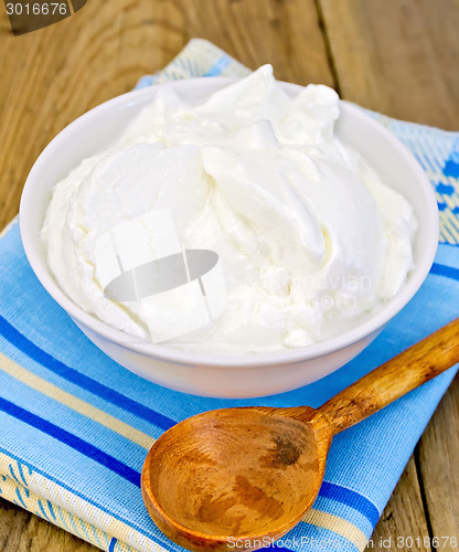 Image of Yogurt in white bowl with spoon on board