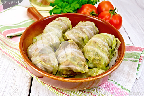 Image of Cabbage stuffed and carrots in ceramic pan on board