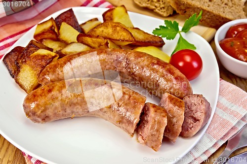 Image of Sausages pork fried with potatoes in plate on board