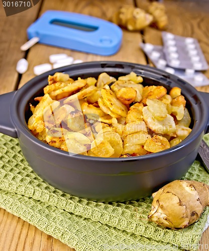 Image of Jerusalem artichokes roasted in pan with meter and pills