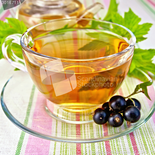 Image of Tea with blackcurrants in cup on tablecloth