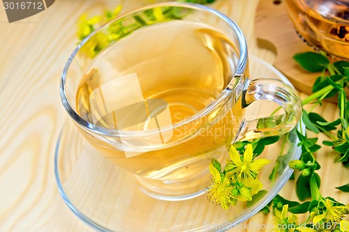 Image of Tea from tutsan in glass cup on board with flowers