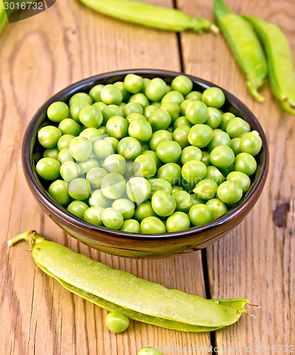 Image of Green peas in brown bowl on board