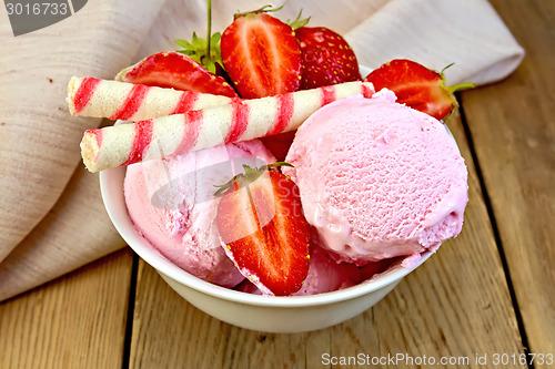 Image of Ice cream strawberry in bowl with wafer rolls on board