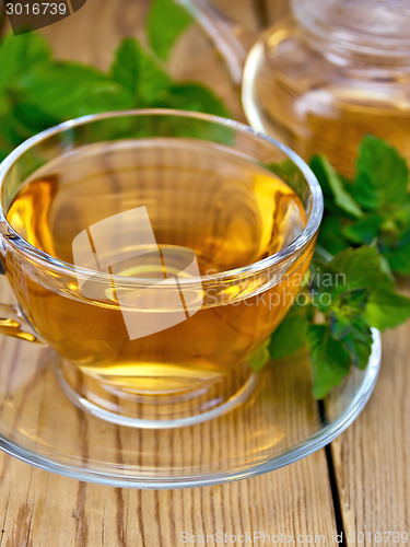 Image of Tea with mint in cup and teapot on wooden board