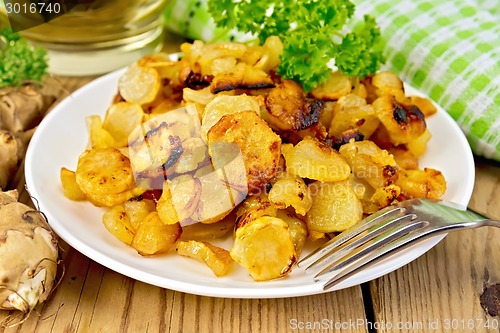 Image of Jerusalem artichokes fried with parsley in bowl on board