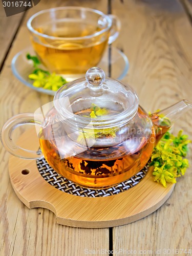 Image of Herbal tea from tutsan in glass teapot on stand with cup