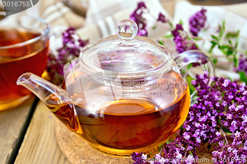 Image of Tea of oregano in glass teapot on board with napkin