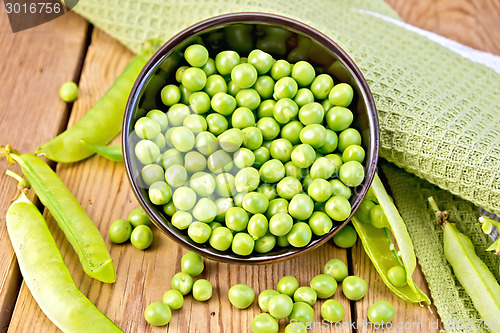 Image of Green peas in brown bowl with napkin on board