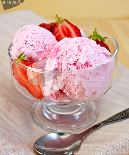 Image of Ice cream strawberry in glass goblet on napkin and board