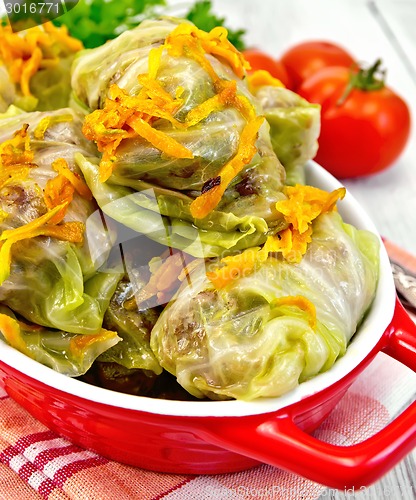 Image of Cabbage stuffed and carrots in red pan on board