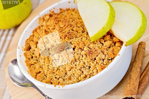 Image of Crumble with pears in bowl on linen tablecloth and board