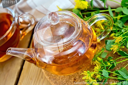 Image of Herbal tea from tutsan in glass teapot with cup on board