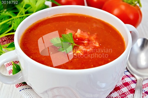 Image of Soup tomato with spoon on napkin and board