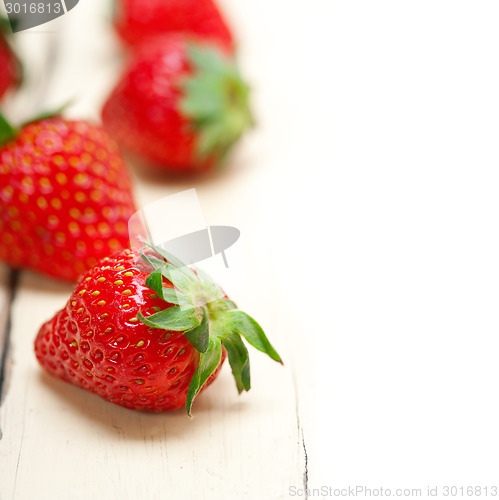Image of fresh organic strawberry over white wood