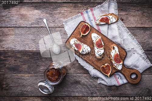 Image of rustic style Bruschetta with jam and Sliced figs on chopping boa