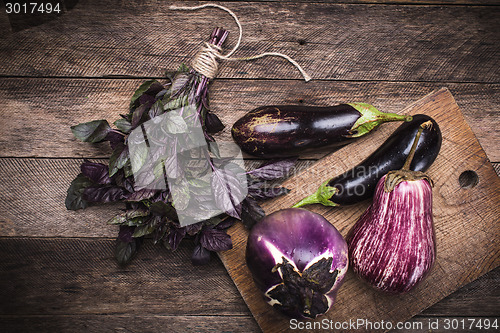 Image of Aubergines and basil on chopping board in rustic style