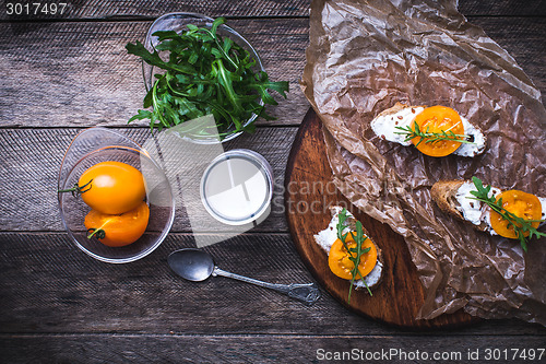 Image of Bruschetta with tomatoes, joghurt and rucola on board 