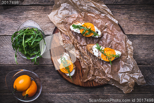 Image of Bruschetta with tomatoes and arugula on board in rustic style