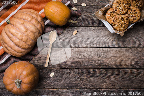 Image of Pumpkins and tasty cookies with nuts on wooden table